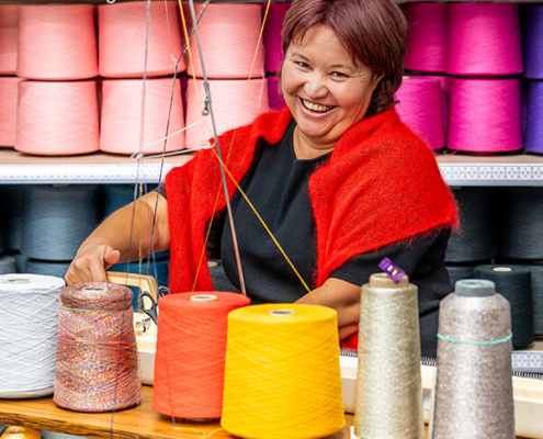 Alia Bekenova in der Strickeria an einer Strickmaschine mit großen Wollspulen