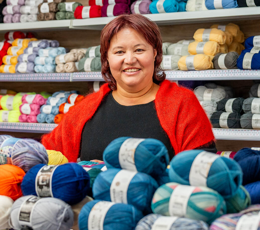 Alia Bekenova in der Strickeria hinter einem Berg Wollknäuel