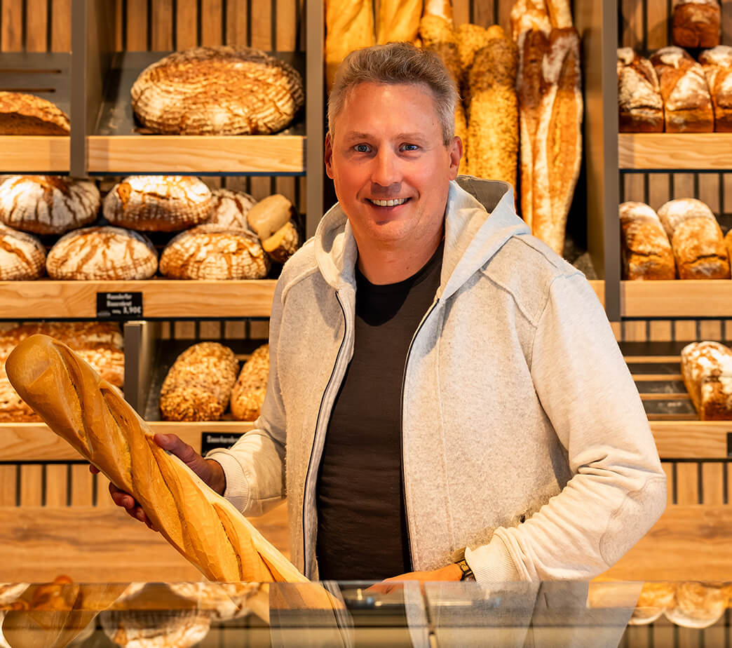 Christian Polster hält ein Baguette in der Hand, in seiner neuen Hauptstelle der Bäckerei, Konditorei, Café Polster in Herzogenaurach