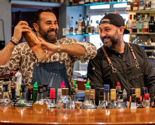 Sami Alijaj mit einem Kollegen hinter dem Tresen seiner HerzoBar in Herzogenaurach beim Cocktail mixen