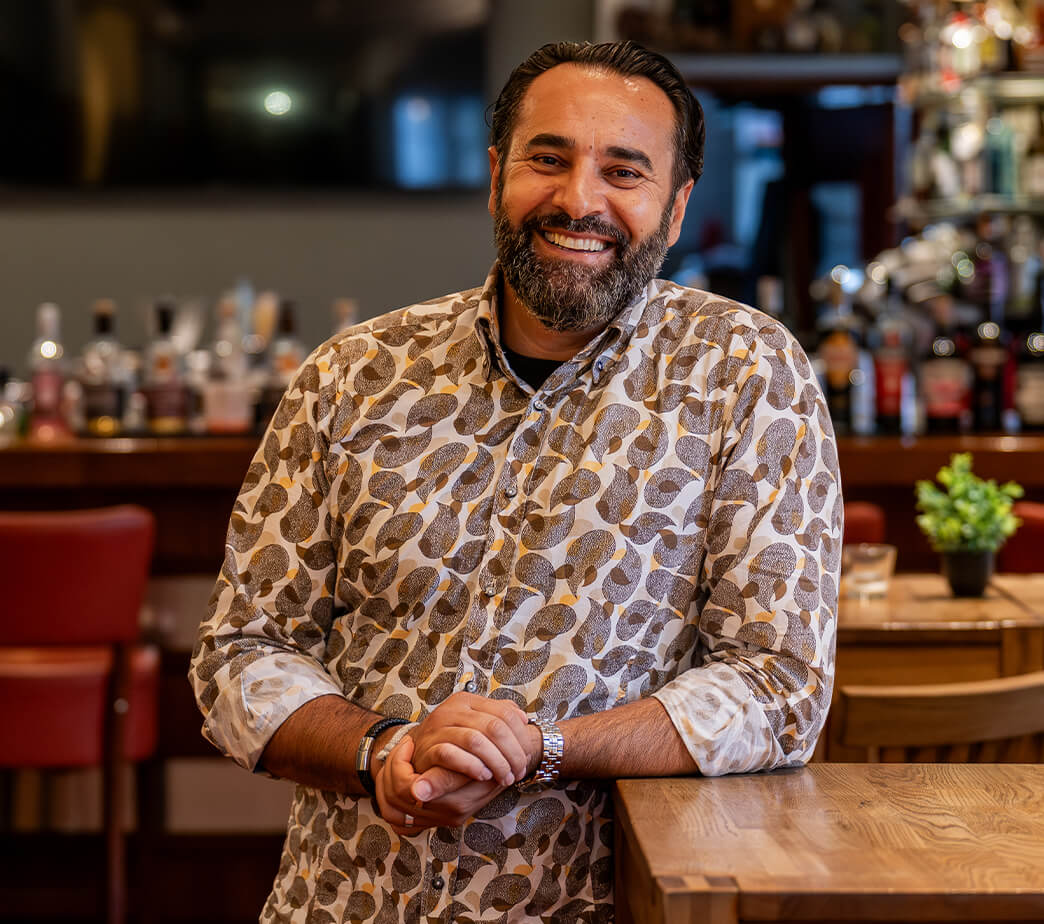 Sami Alijaj, Inhaber der HerzoBar, lehnt an einem Stehtisch in der HerzoBar