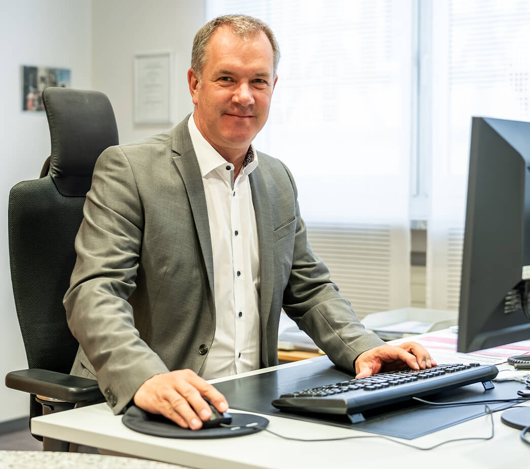 Armin Trippner von der Sparkasse Herzogenaurach, Sponsor der Initiative herzoBotschafter:innen hinter einem Schreibtisch sitzend